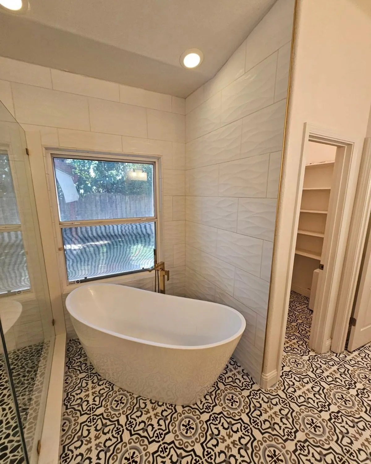Custom bathroom remodel with freestanding soaking tub and patterned tile floor — by Palafox Prestige Construction