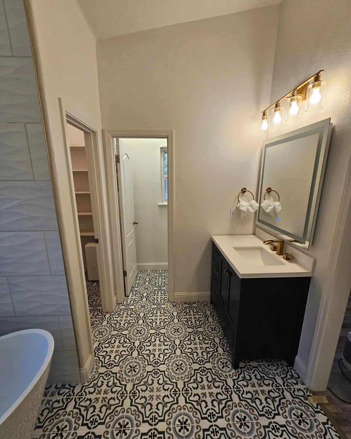Custom master bathroom remodel with freestanding tub, patterned tile, and gold fixtures — by Palafox Prestige Construction